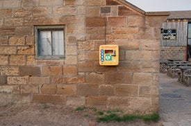 Photo of a yellow defibrillator unit attached to an old sandstone building outside Whitby Brewery