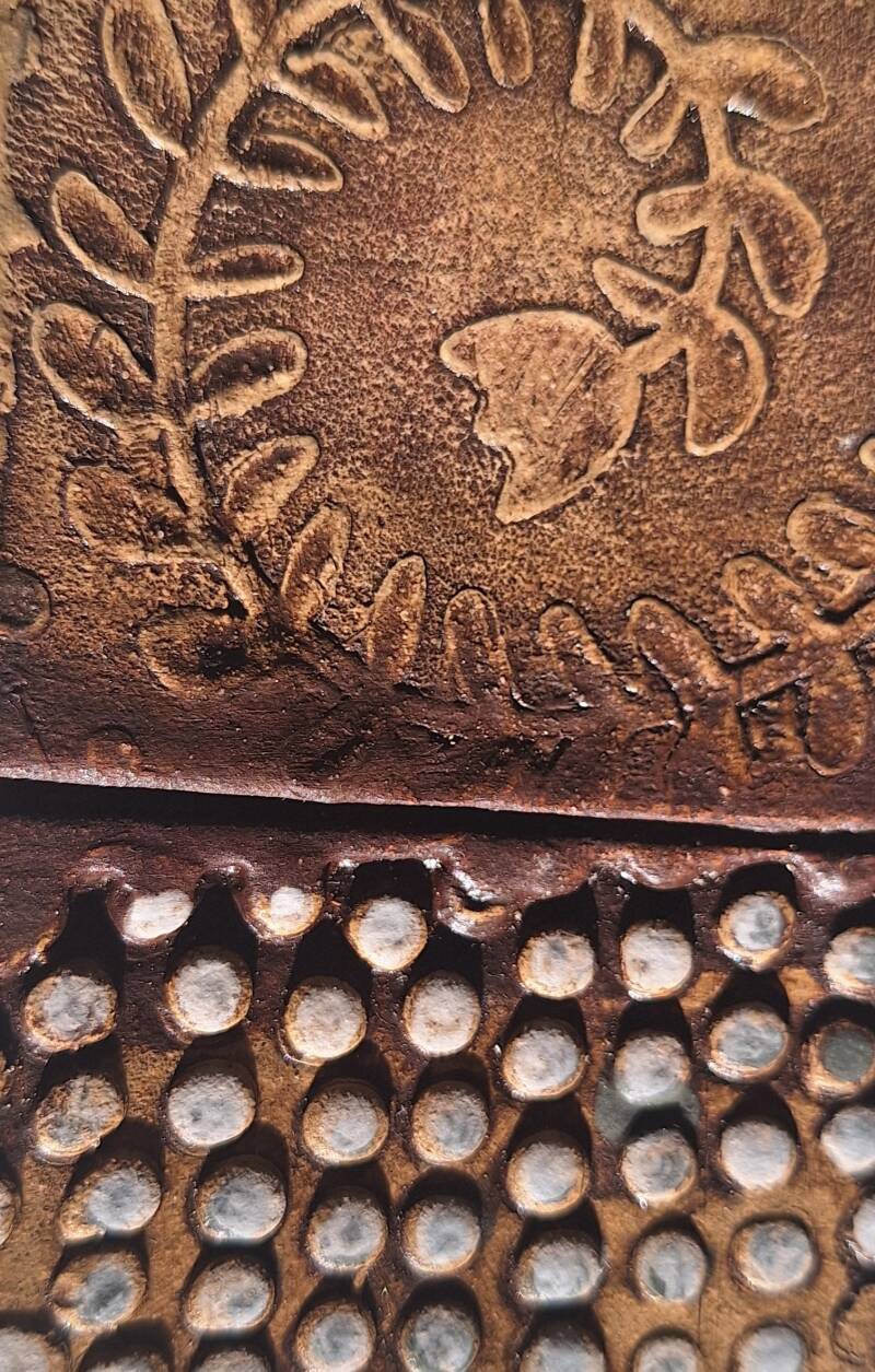 detail of a dish using a commercial stencil and a handmade stamp with red iron oxide and silver underglaze