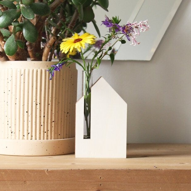 Housewarming cadeaus! Op de foto een houten vaastje in de vorm van een huis waar een klein bloemetje in past.