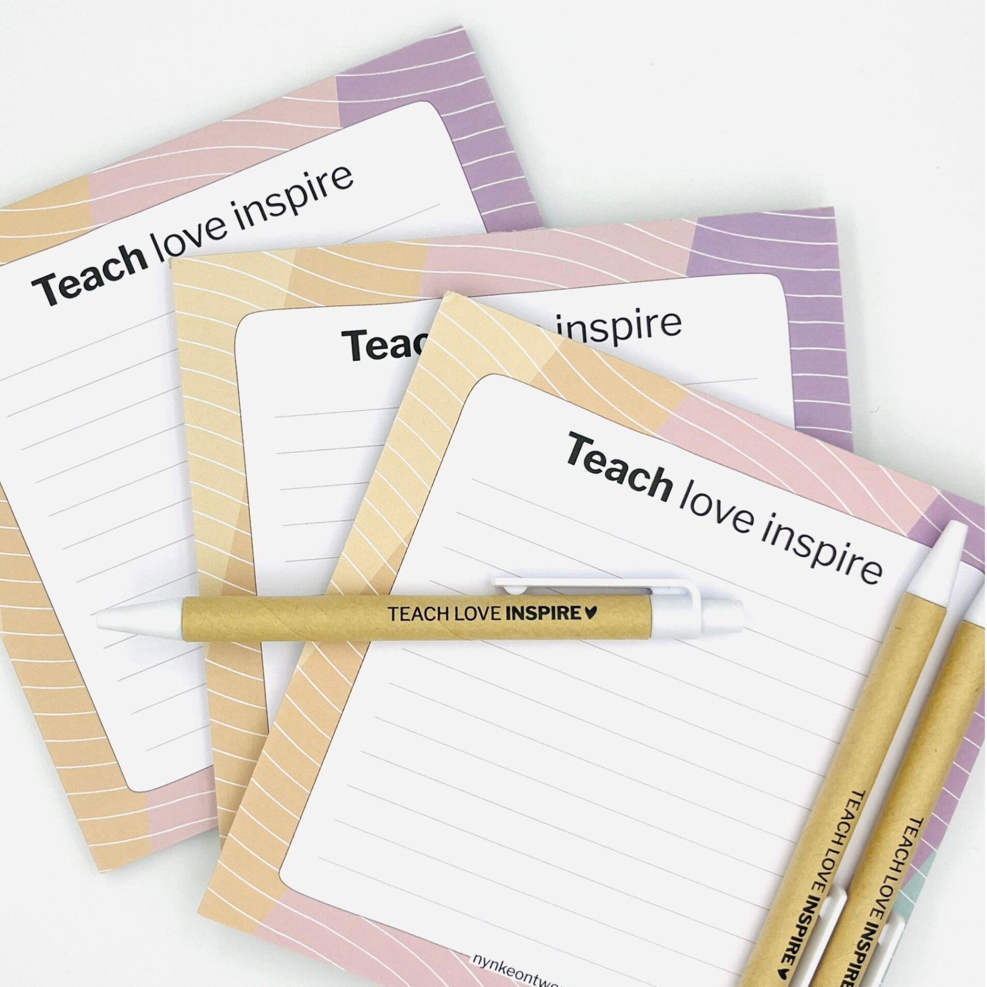 Cadeaus om de juf en meester te bedanken. Op de afbeelding een notitieblok en pen met de tekst Teach Love Inspire