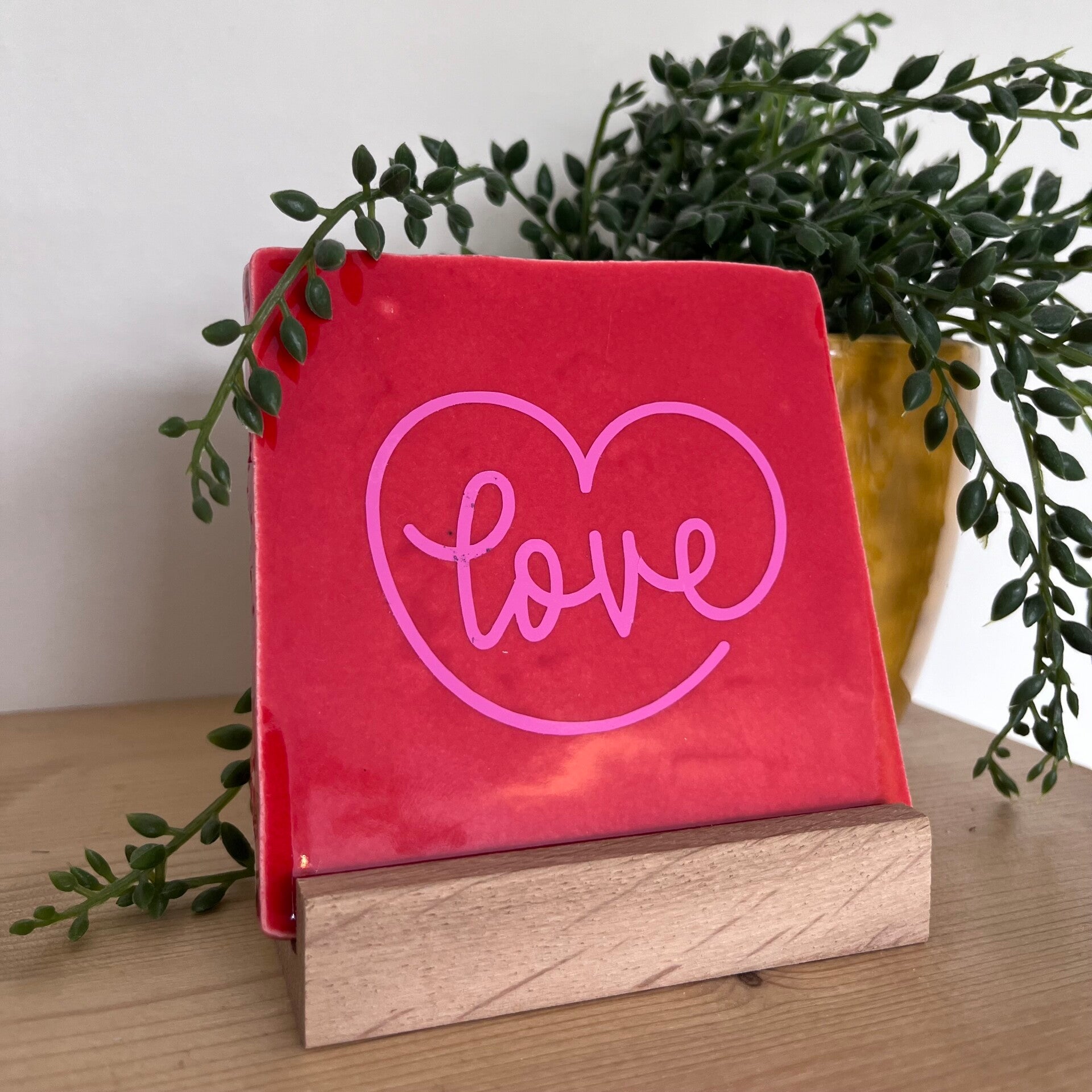Liefdevolle cadeaus! Op de afbeelding een rood tegeltje met in roze Love erop