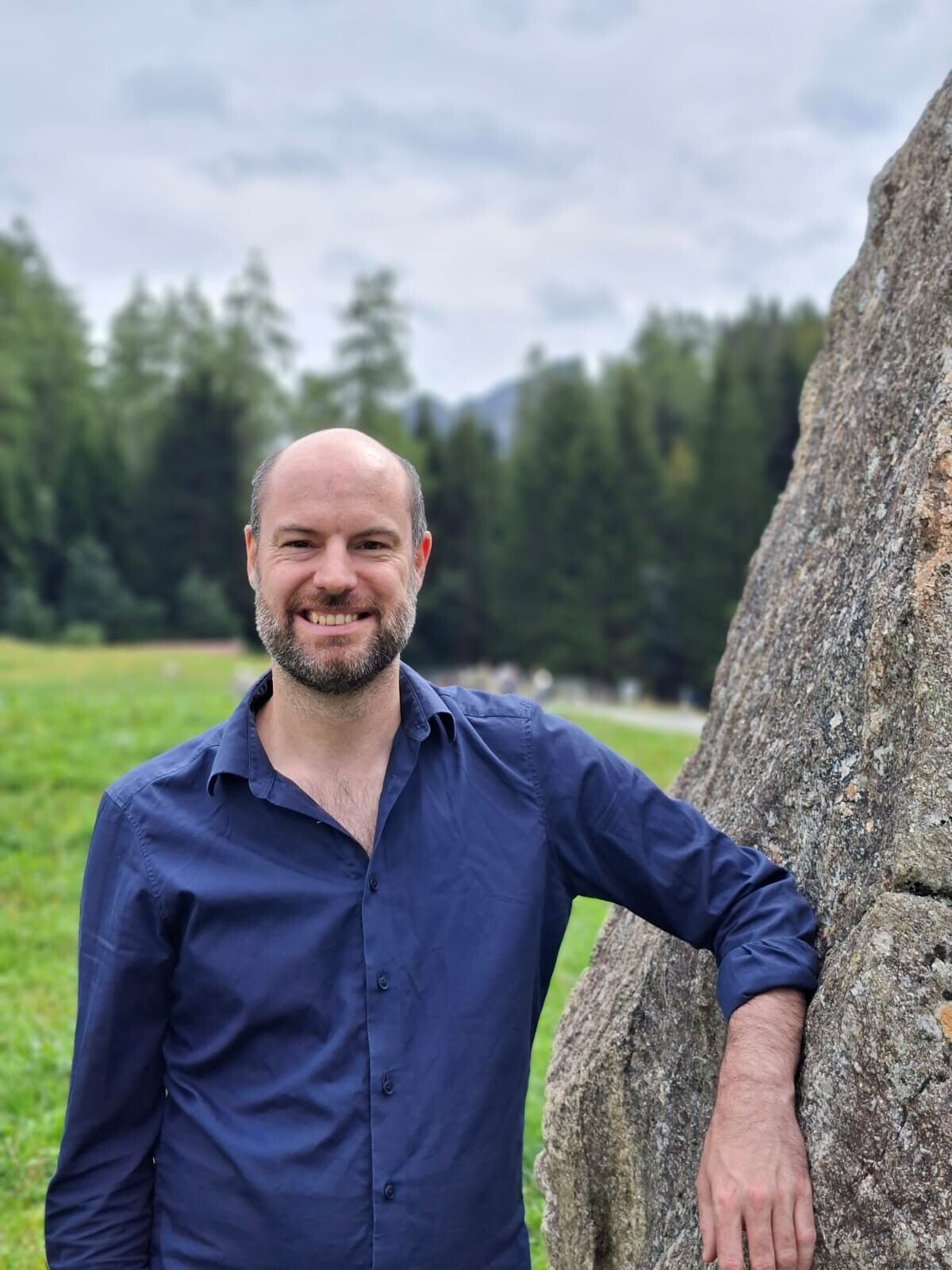 Werbetexter Gernot stehst lächend vor einem beigen Hintergrund