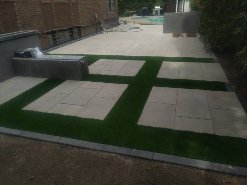Artificial grass installation around paving stones in Montreal, Quebec – Capo Surface