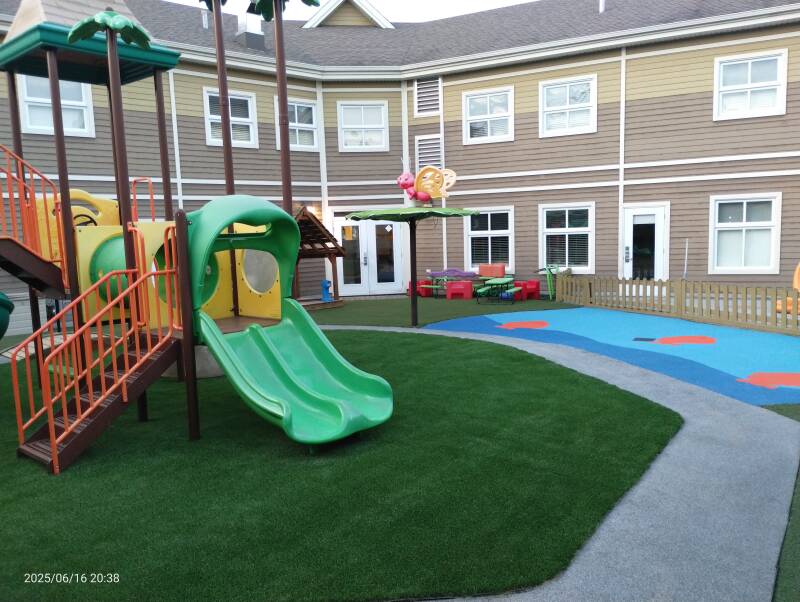 Daycare playground with combined rubber surface, artificial turf, and play structure