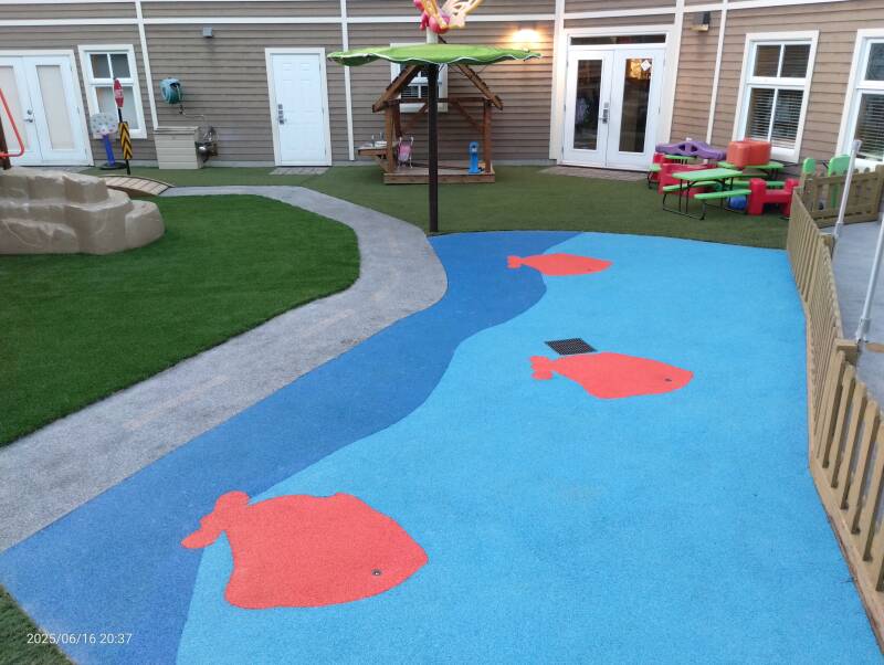 Rubber and artificial grass playground area with play module at daycare