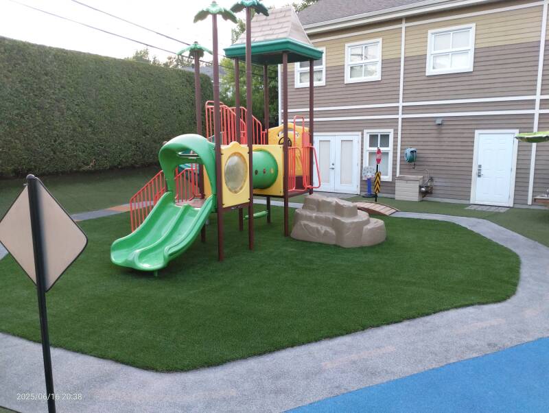 Daycare playground featuring rubber surface, artificial grass, and play equipment