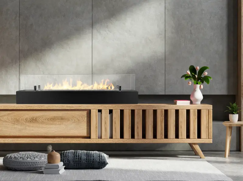 Bio-ethanol haard met glas van 700 mm op een houten dressoir in een moderne woonkamer. Ernaast staat een vaas met tulpen en enkele boeken