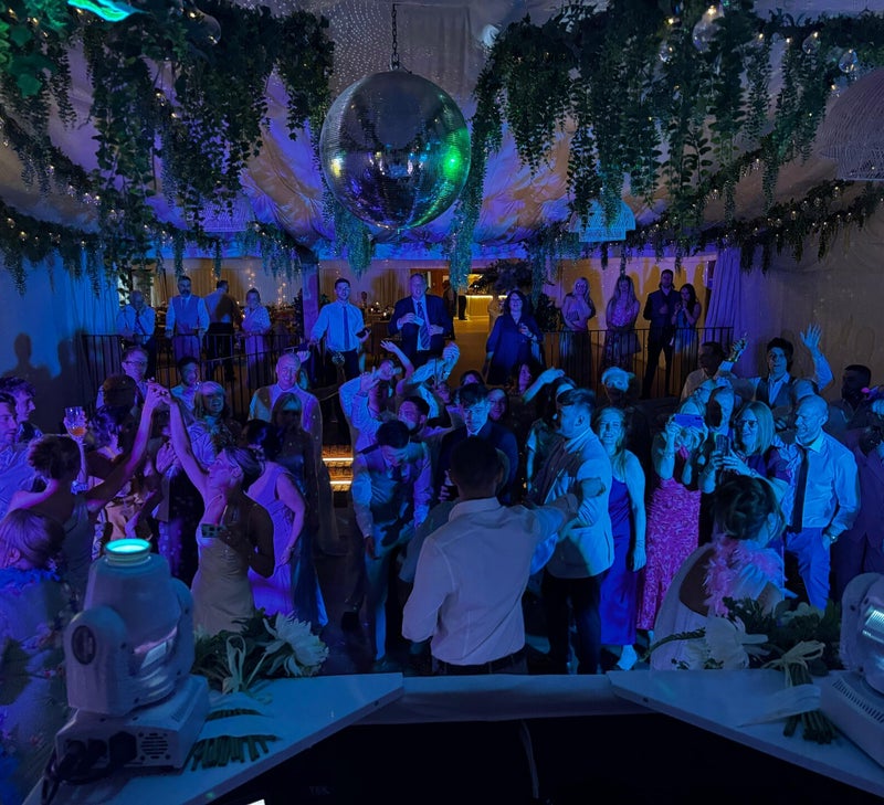 Wedding guests filling the dancefloor beneath flowers and a mirrorball