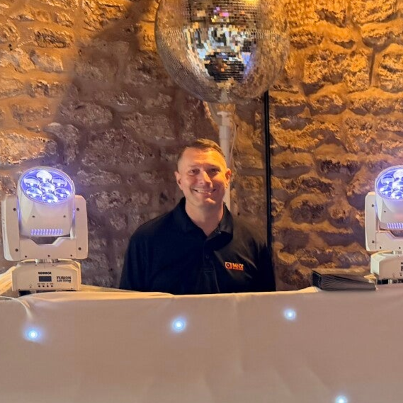 MHX DJ Chris Gray behind a white booth at an event