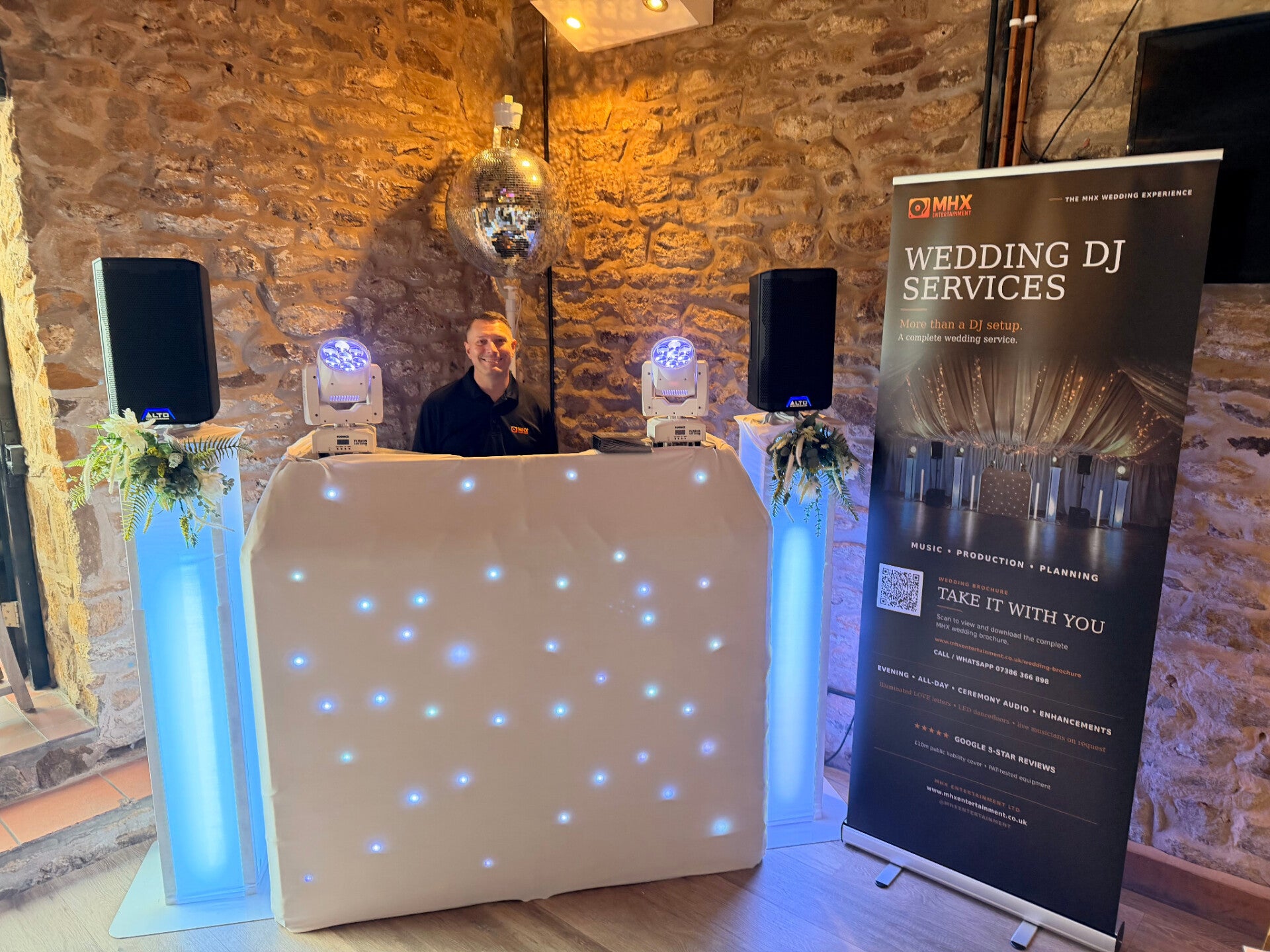Chris, an MHX wedding team DJ, behind a white starlit booth at a wedding fayre