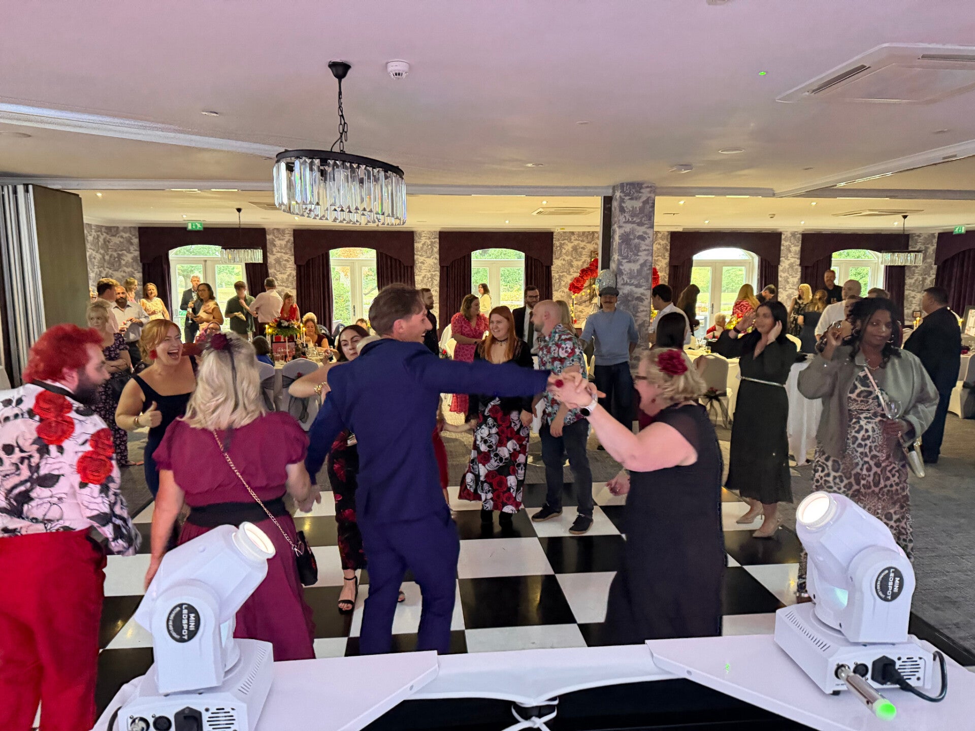 Wedding guests dancing in front of an MHX DJ setup on a black-and-white dancefloor
