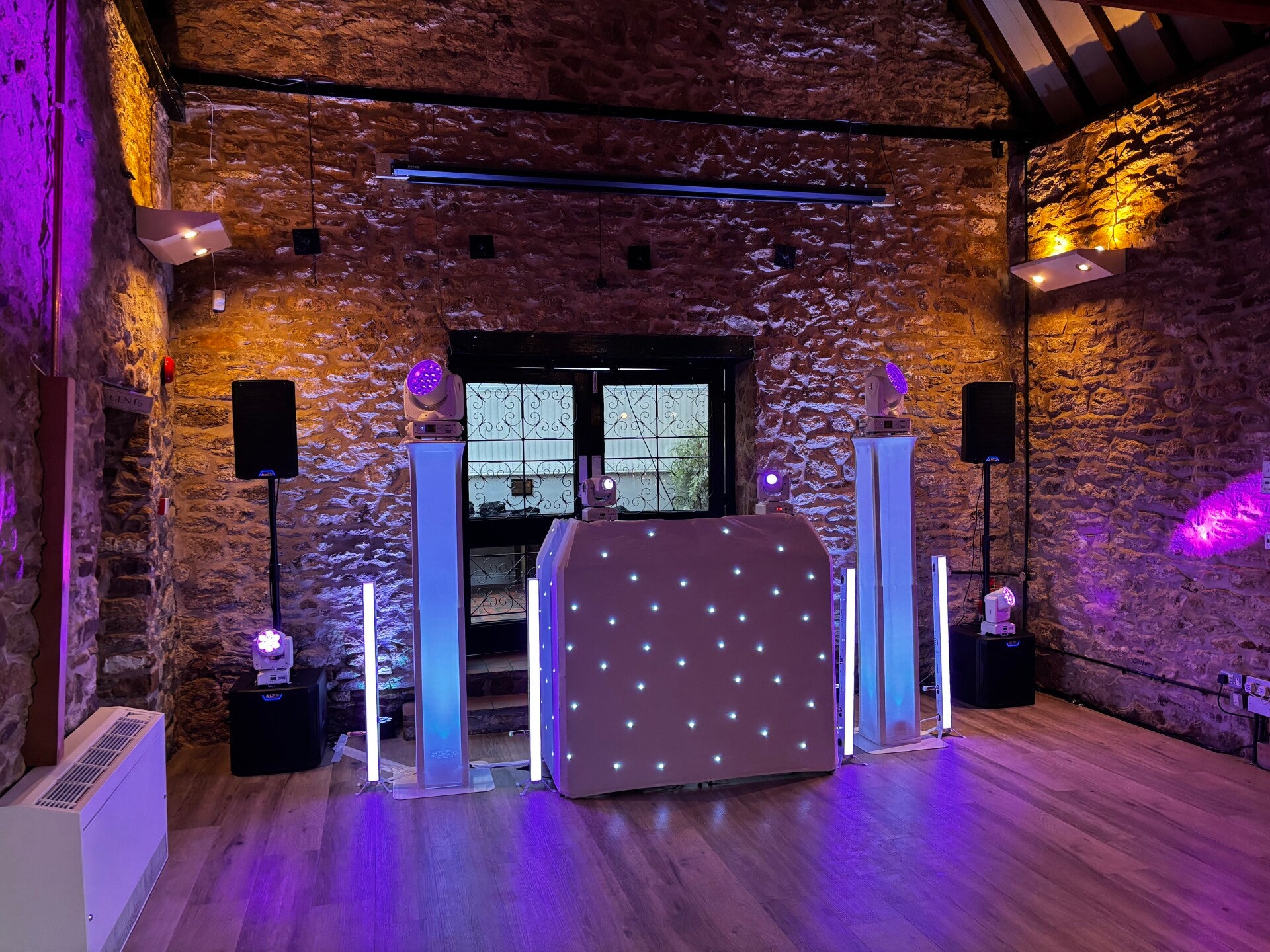 Premium evening wedding DJ setup with booth and lighting