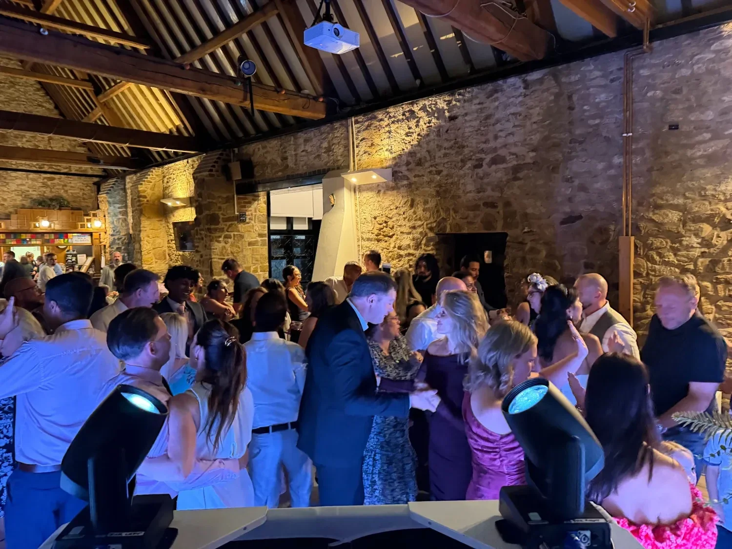 Wedding guests dancing together inside a stone barn