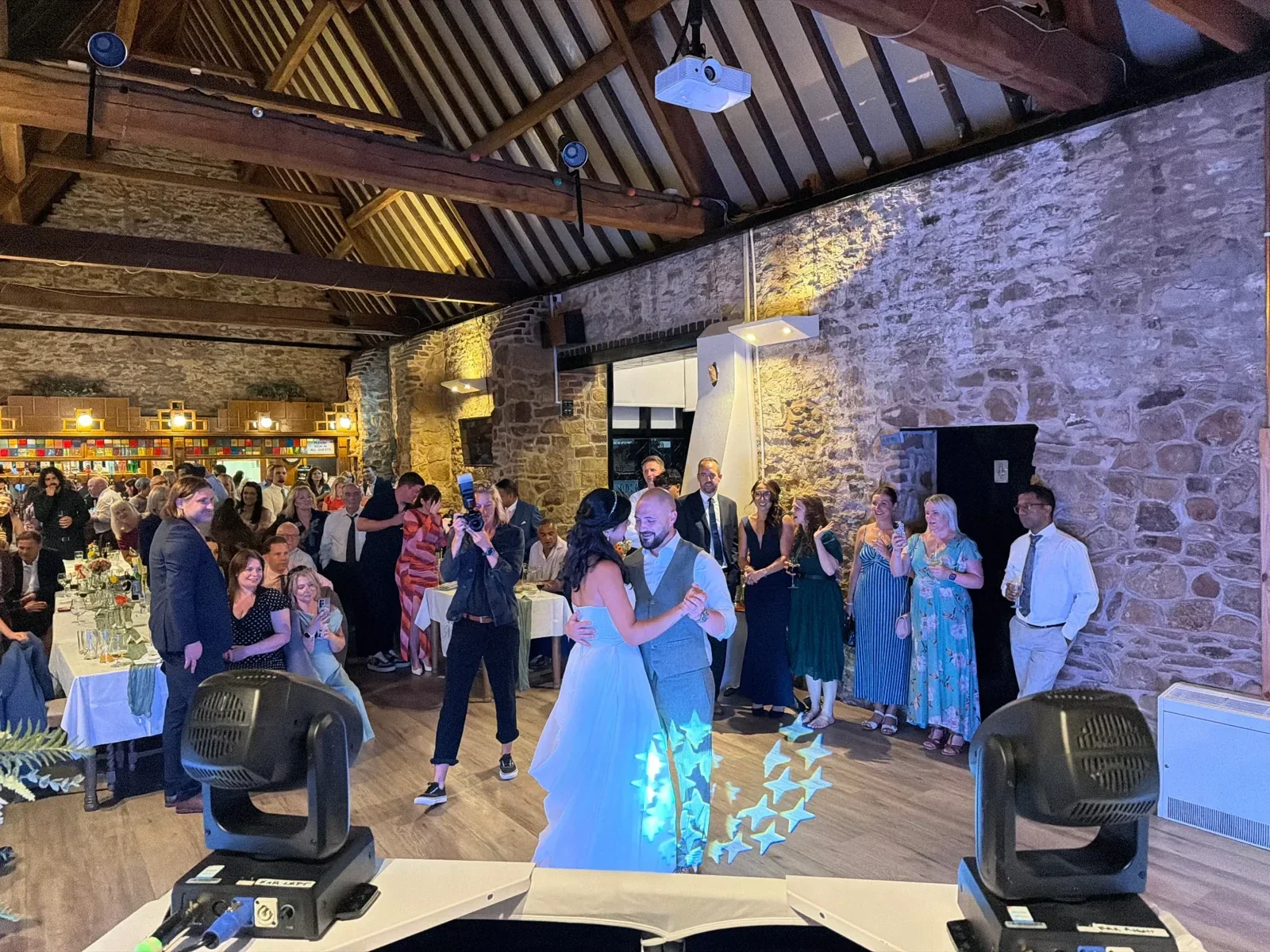 Couple sharing their first dance as wedding guests gather in a barn at an MHX event