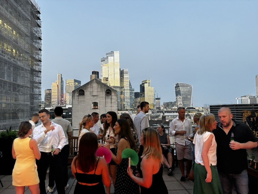 Guests dancing at the Canaccord Wealth rooftop party at 88 Wood Street, with the City skyline behind