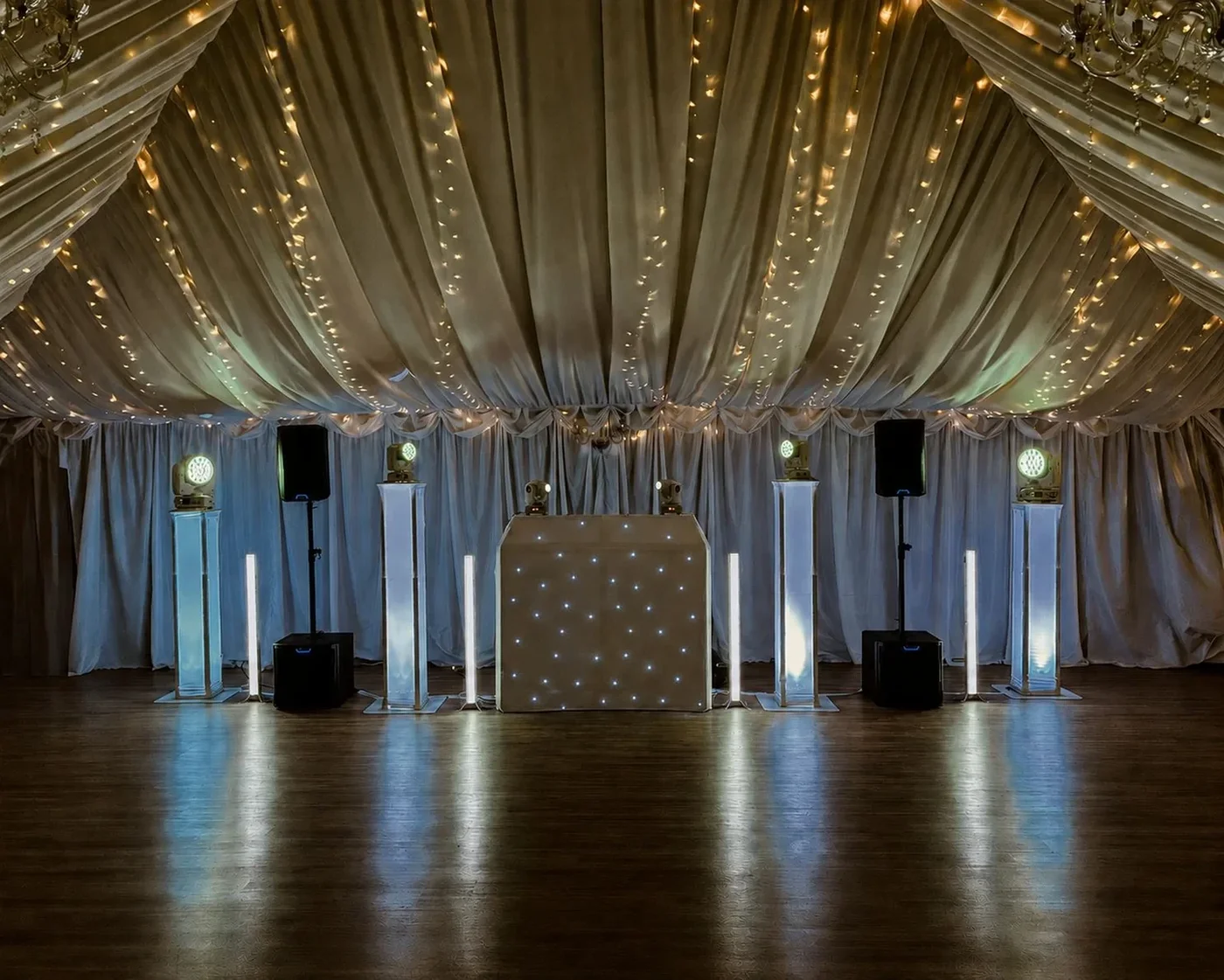 MHX white wedding DJ setup beneath a warmly lit draped ceiling
