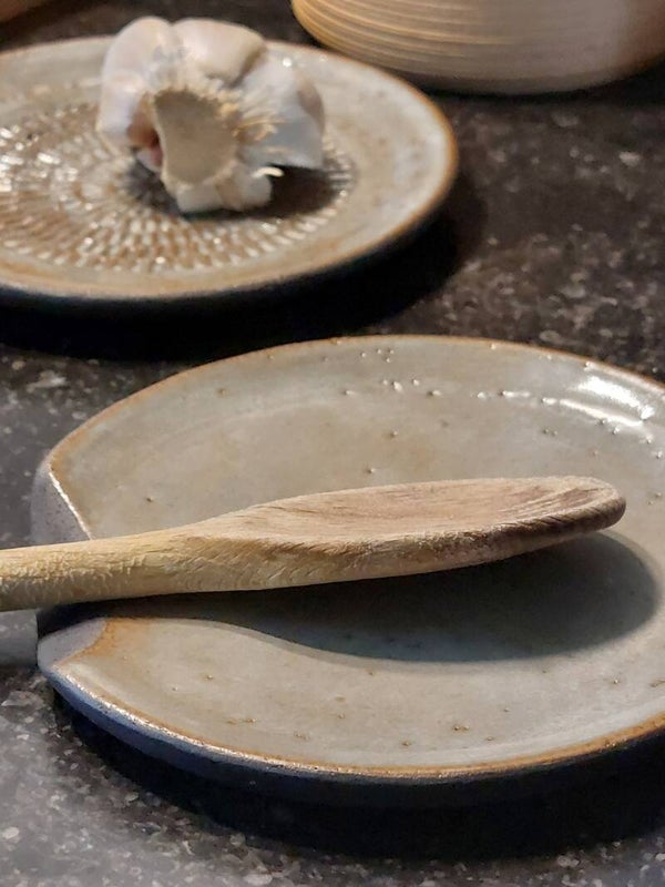 Bord voor lepel in zwarte klei met een groen, goud, beige kleurige glazuur