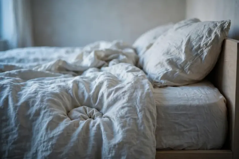 Lit vide au petit matin avec un creux au pied du lit, image du sommeil bouleversé après la perte d’un animal.