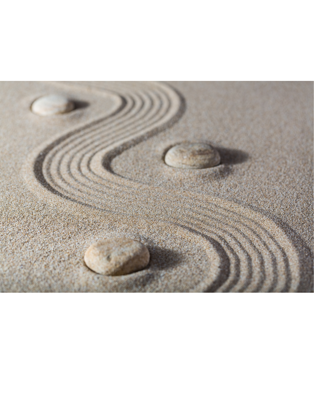 Vier Steine liegen in geschwungenen Linien in feinem Sand und symbolisieren Gleichgewicht, Ruhe und ganzheitliches Wohlbefinden
