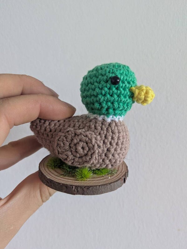Canard sur socle en bois et végétation