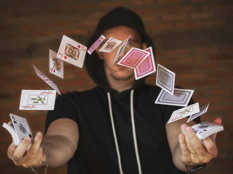 Man performing a card trick, the cards are flying in a half circle between his hands.