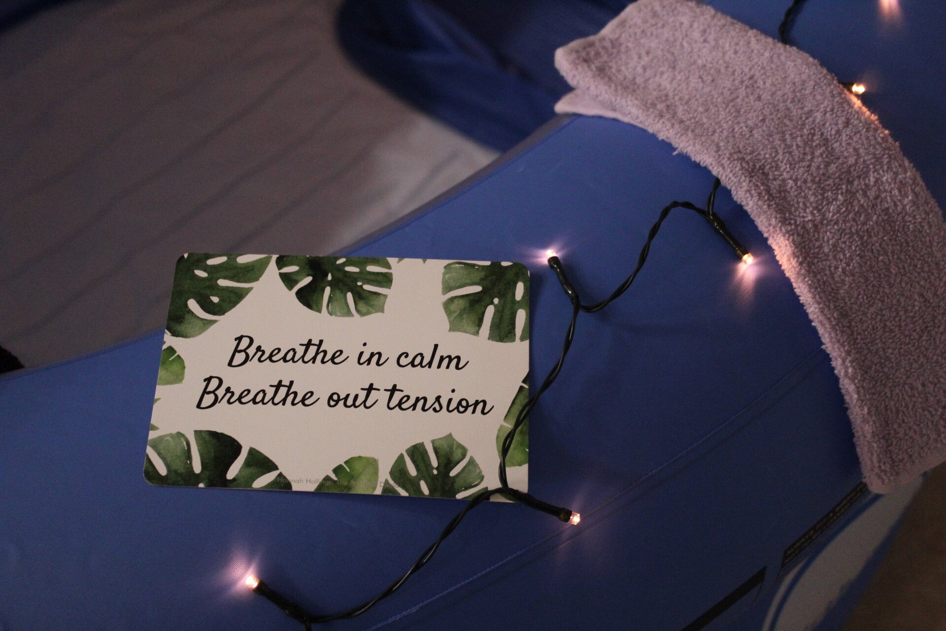 colour image of a postcard sized birth affirmation "breath in calm, breath out tension" resting on the side of a blue birth pool. Image taken by https://www.mamakat.co.uk/ founder member of Cheshire Home Birth Alliance