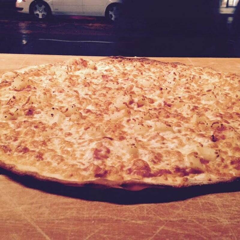 "Goldie's Pizza signature menu asset: A full-overhead view of a classic Hawaiian pizza displaying signature crust blistering and evenly distributed ingredients."