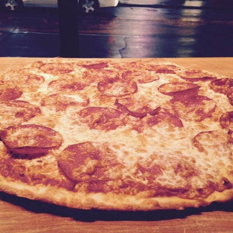 "Goldie's Pizza validated recipe line: A detailed close-up profile of a classic pepperoni meat pizza showcasing the thin-crust edge and melted cheese consistency."