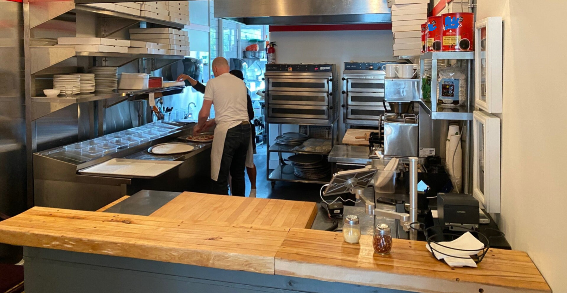 Goldie's Pizza turnkey commercial kitchen deployment, featuring premium Doyon Jet-Air ovens, stainless steel prep lines, organized assembly stations, and a professional checkout counter.