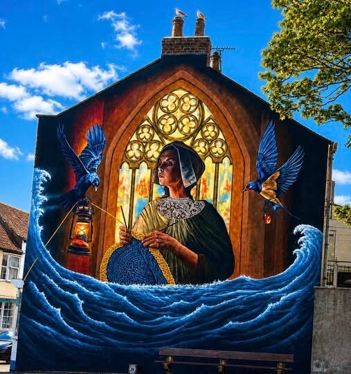"Gansey Girl". Inspired by the famous harbour sculpture, it pays homage to the tight-knit fishing communities and the tireless women who hand-knitted the distinctive woollen patterns for their loved ones at sea. It is flanked by illustrations of the histo