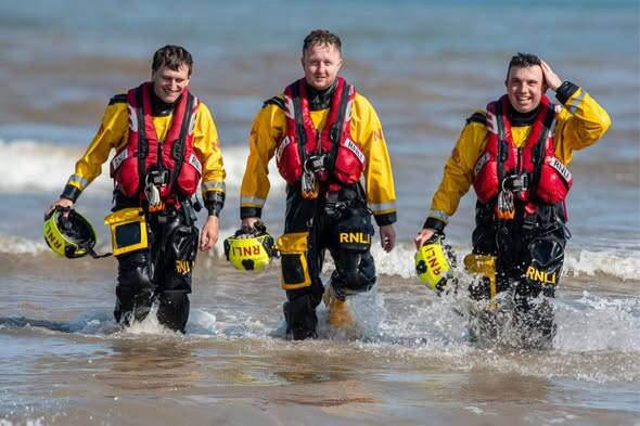 RNLI lifeboat crew on Bridlington beach responding to multiple incidents involving missing children and paddleboarders, promoting beach safety wristbands for families.