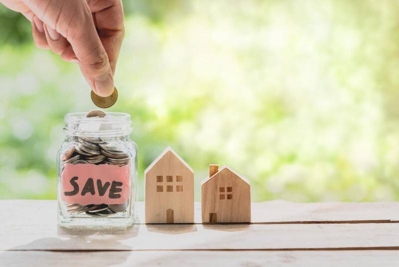 Savings jar and wooden houses symbolising financial support.