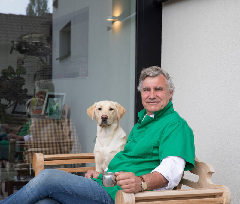 dierenarts met hond buiten aan de praktijk zittend op een bank