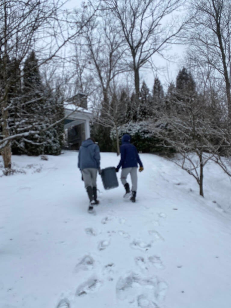 Greenwich Composting Project Addison and Noah carrying kitchen scraps up snowy hill to add to compost pile