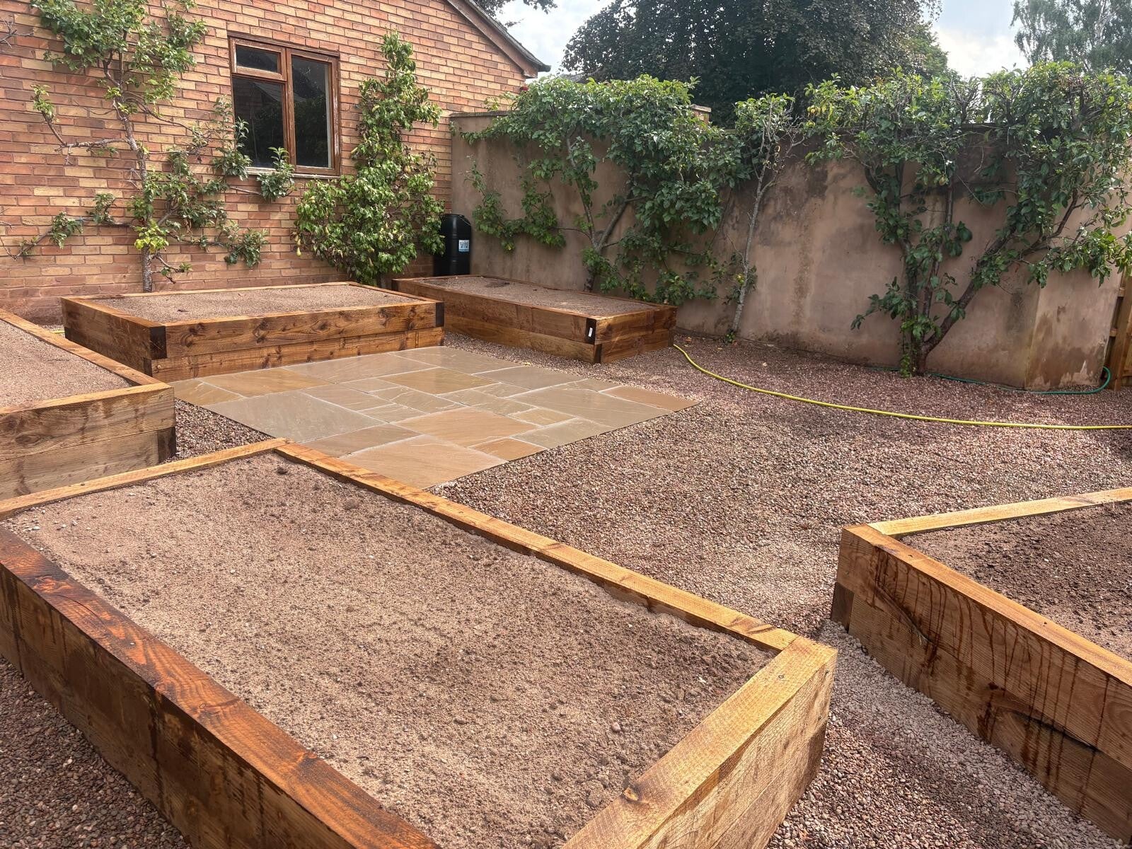 Landscaped garden with patio and raised timber seating in Belbroughton