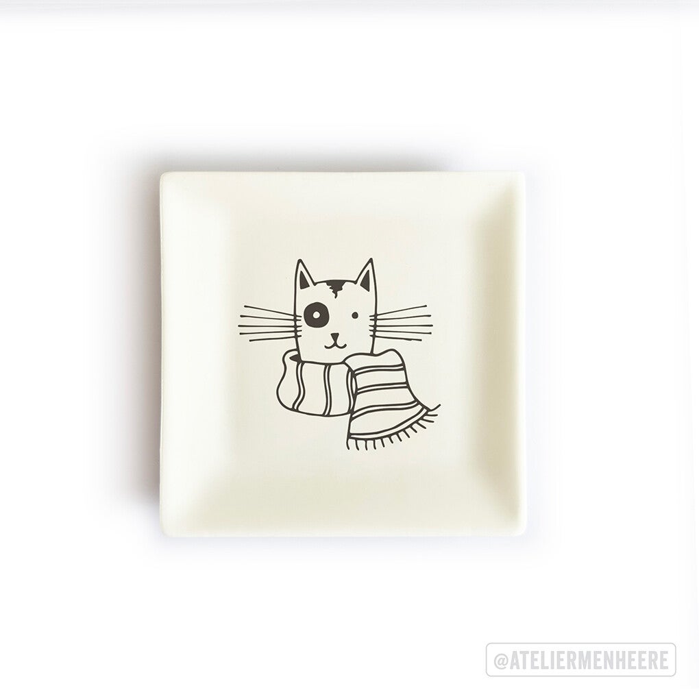 Vierkant, wit theetipje met daarop de illustratie van een kat met een feesthoedje op en een ballon aan zijn staart.