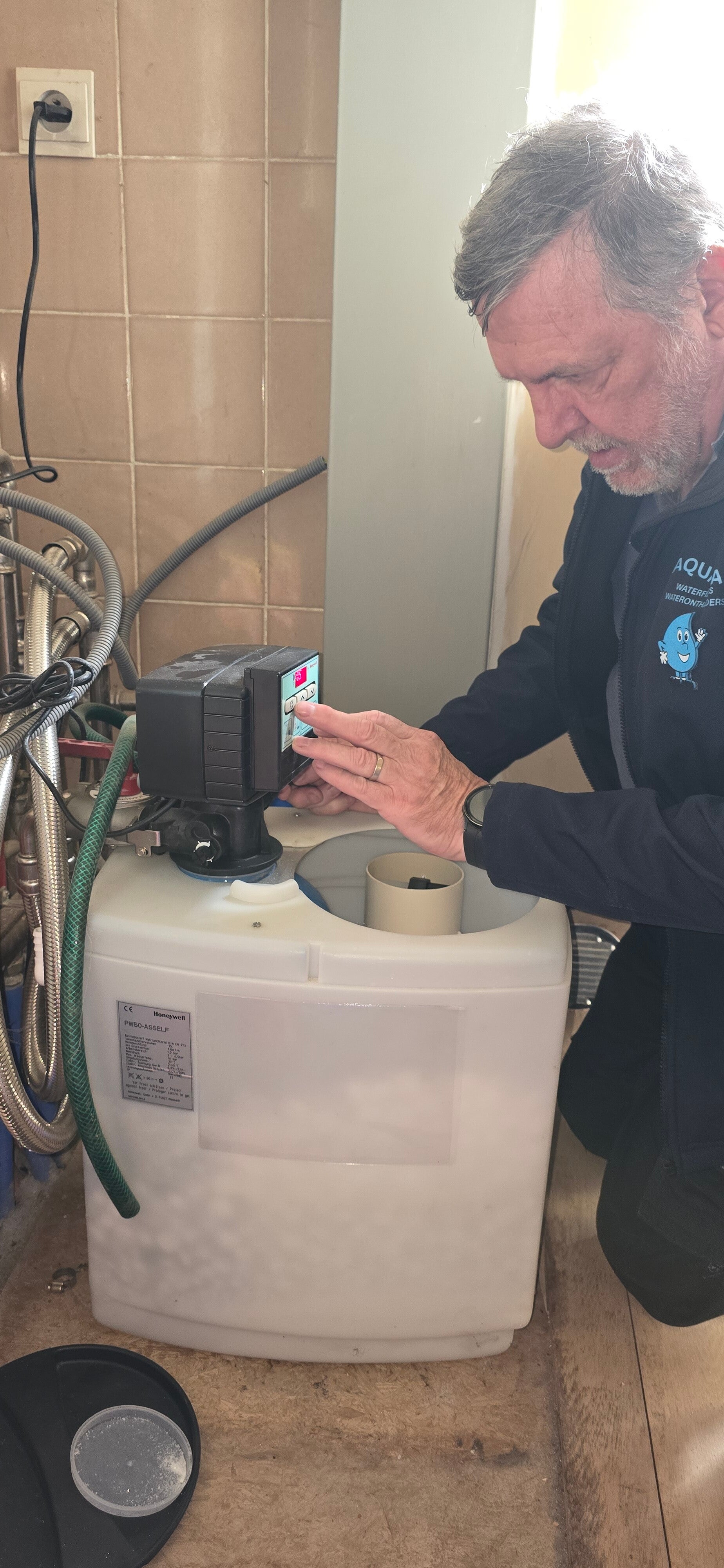 Zaakvoerder van Aquaman voert persoonlijk onderhoud uit aan de besturingsklep van een waterontharder.