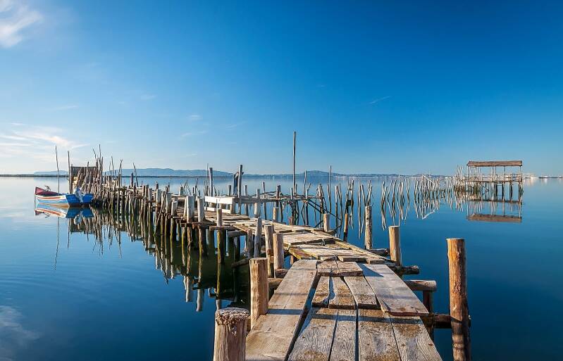 O porto de palafitas de Carrasqueira em Portugal. Tudo sobre o mar azul. Um barco esta la tambem.