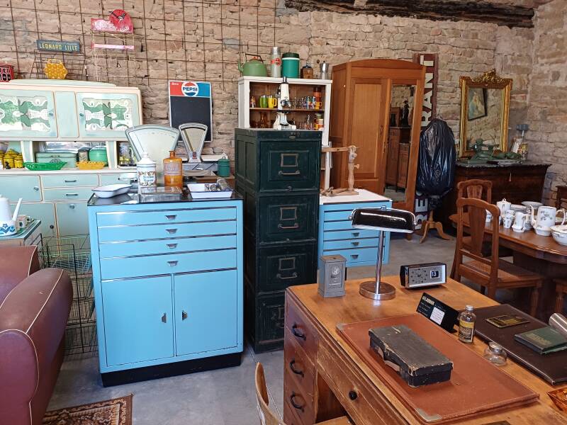 Un ndouble bureau en bois devant un meuble de vétérinaire bleu, un buffet vintage et un meuble de classement en métal