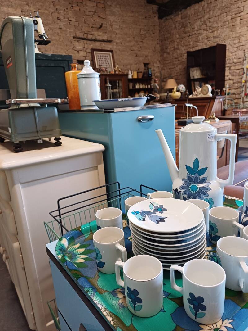 Vaisselle vintage avec fleurs bleues devant des meubles anciens