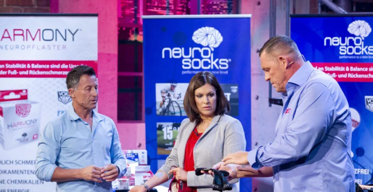 Wolfgang Cyrol und Hans Enn präsentieren gemeinsam mit Katharina Schneider die Neuro Socks in der österreichischen TV-Sendung „2 Minuten 2 Millionen“, wo die innovativen Socken potenziellen Investoren vorgestellt und demonstriert werden.