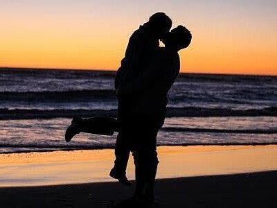 Sexual compulsivity - silhouetted couple embrace on a beach in twilight