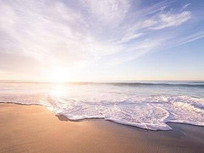 Premature ejaculation - a sunlit beach scene with the white foam of broken waves washibng up on the sandy beach