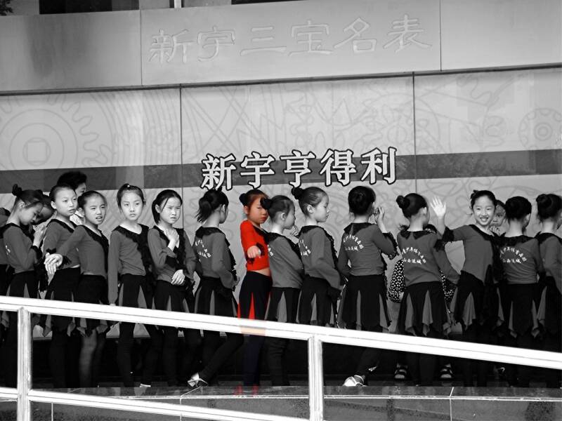 meisje in groep sportmeisjes kijkt en wijst naar de fotograaf in Peking