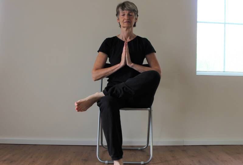 houding de boom, zittend op een stoel bij stoelyoga