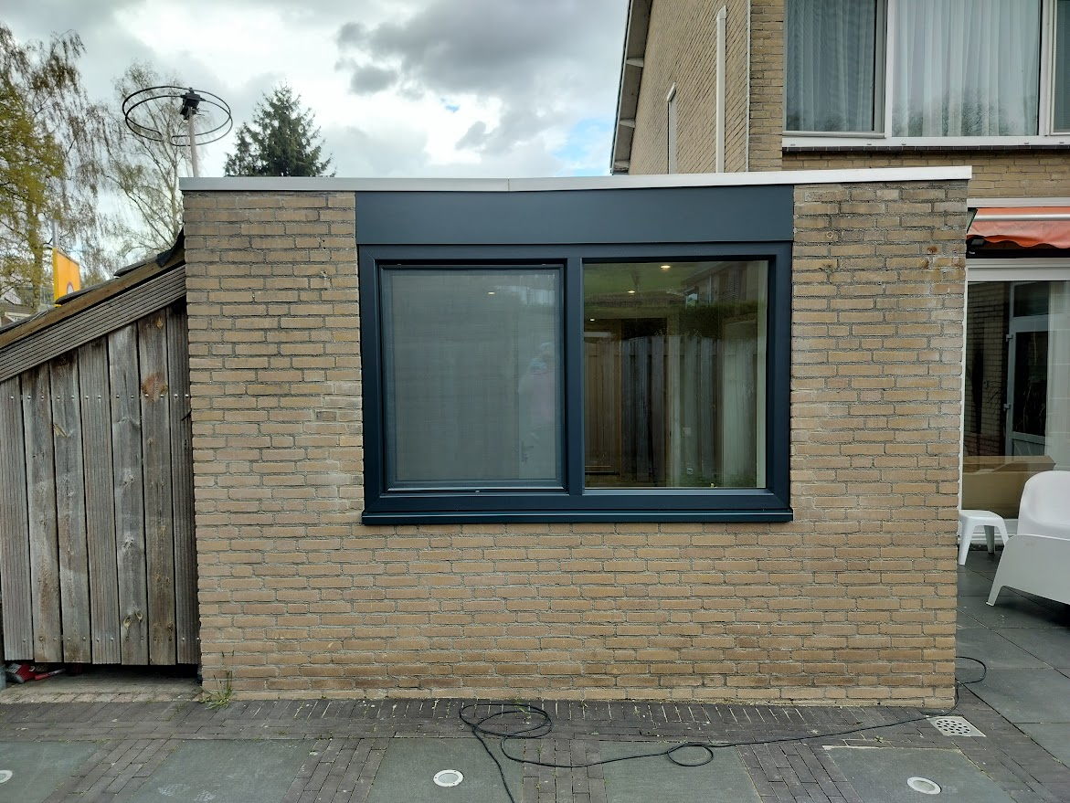 Een zwart kozijn geplaats aan de buitenkant van een woning