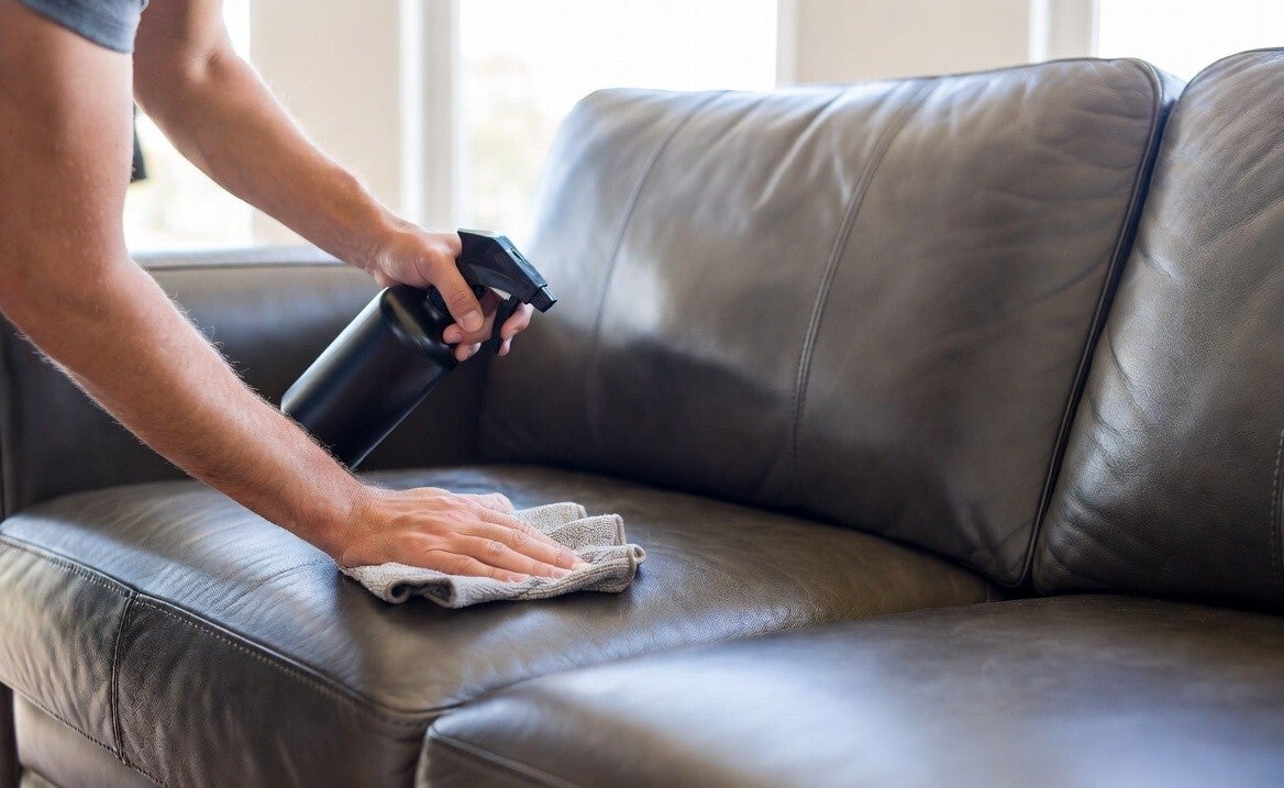 mans arms and hand cleaning a leather lounge