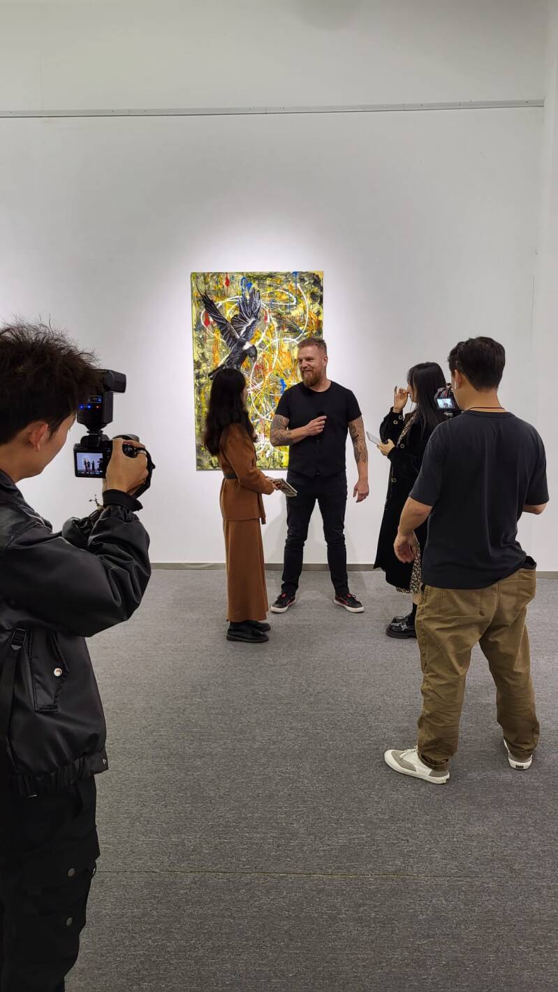 Willem Vos being interviewed in front of one of his bird paintings at Hong Art Museum.