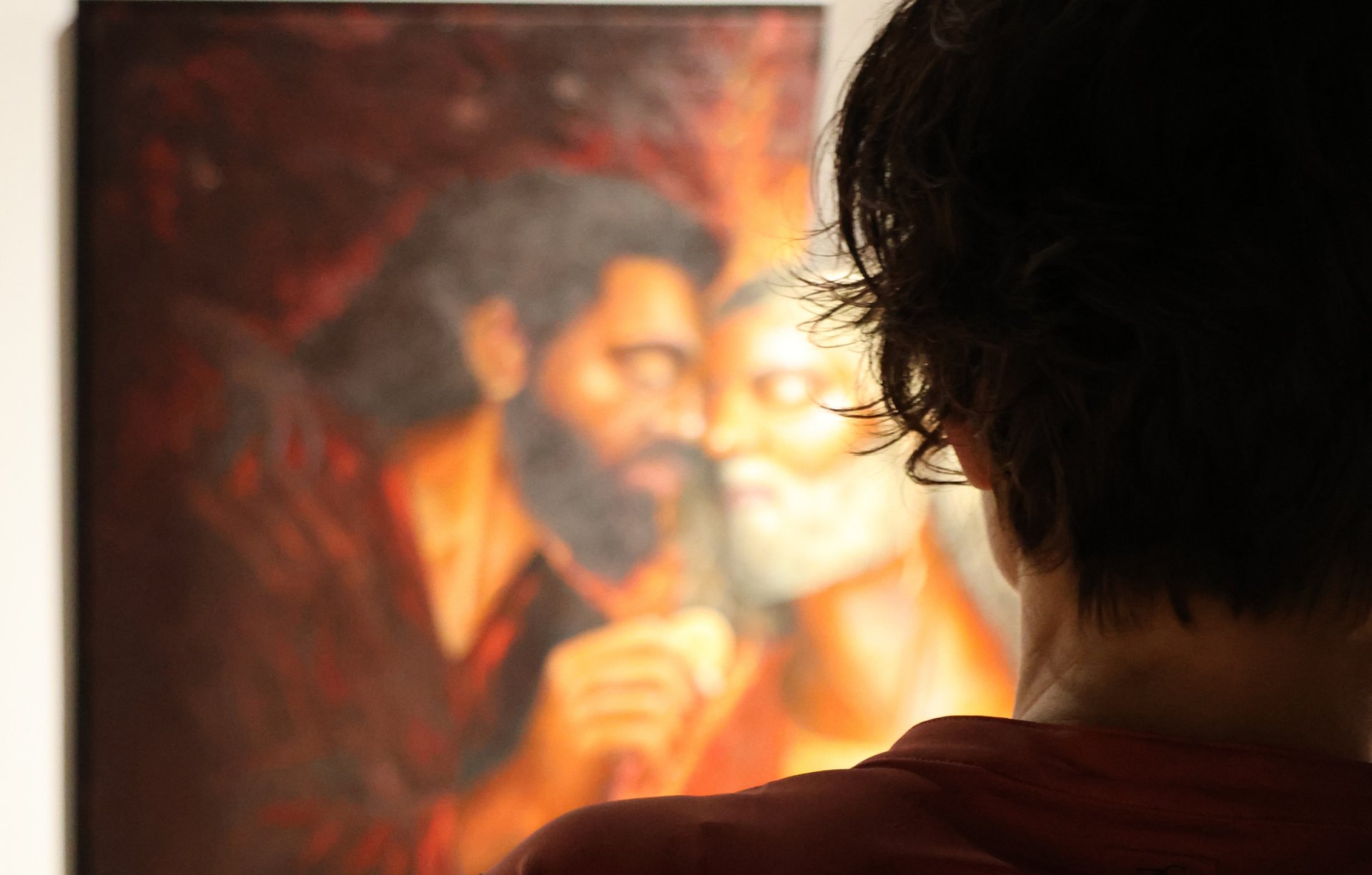 Bezoeker kijkt naar een detail van een Passie-schilderij van Willem Vos tijdens zijn eerste solotentoonstelling in Dwingeloo.