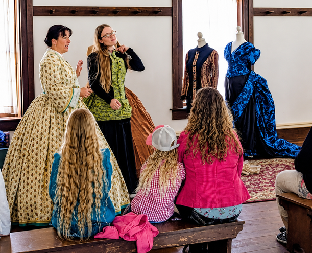 Historical fashion demonstration displaying changing 19th-century clothing silhouettes including Victorian hoops, crinolines, and bustles from 1860 to 1890.